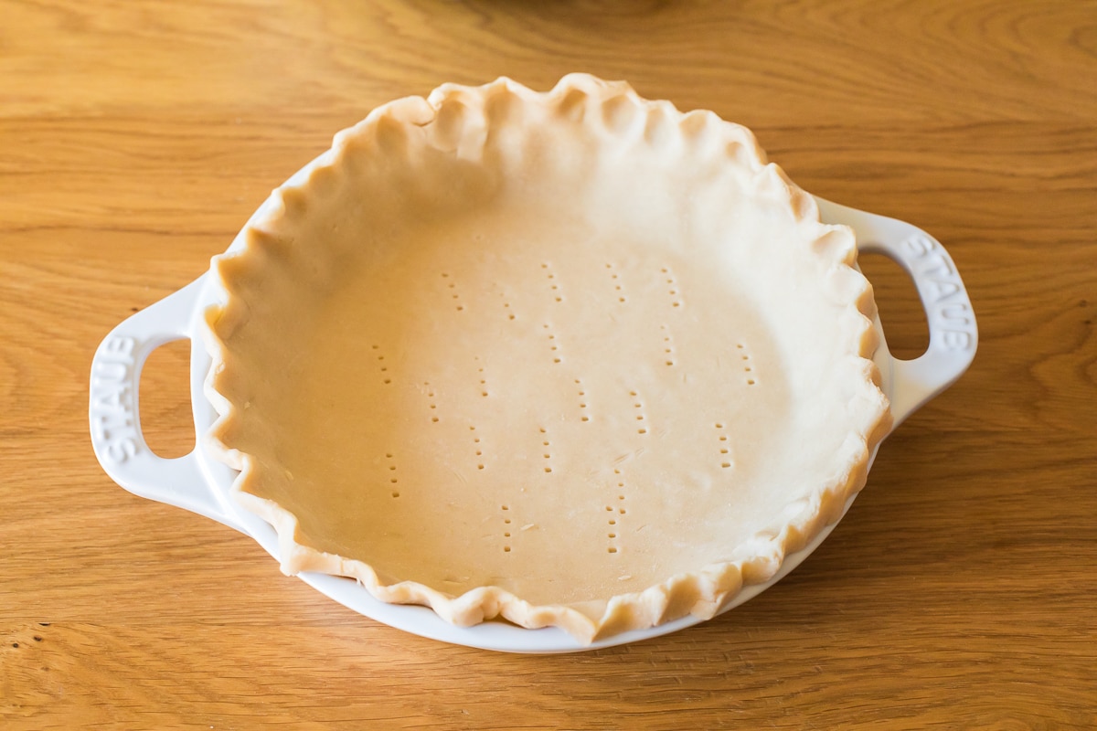 raw pie crust in a staub pie pan.