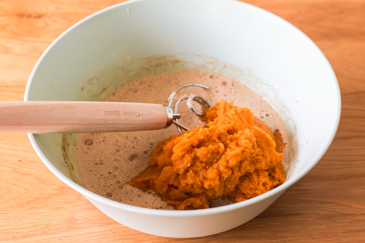 making dairy free pumpkin pie filling in a light green bowl with a Danish whisk in it.