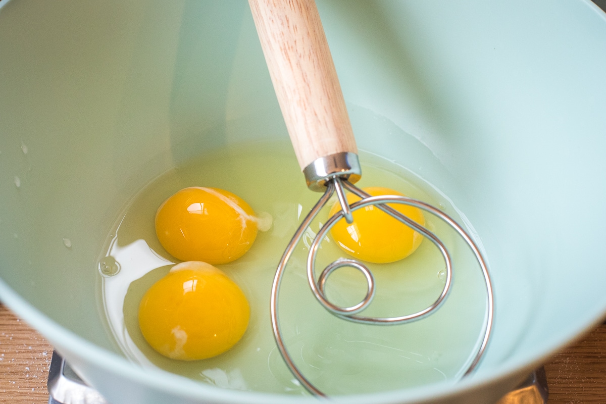 3 eggs and a danish whisk in a bowl.