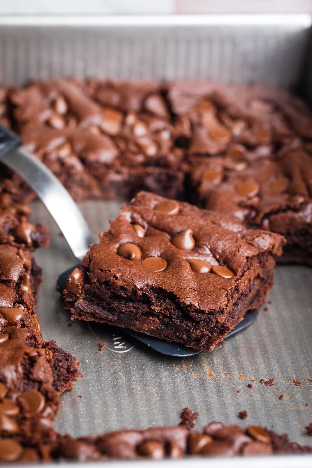 brownie on a spatula inside a baking pan with more brownies.