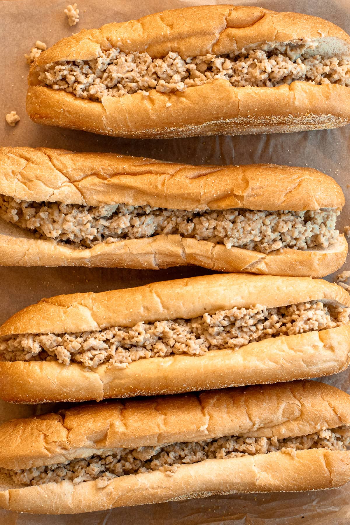 Close up of four chicken cheesesteaks with ground chicken and Cooper Sharp cheese on Amoroso rolls.
