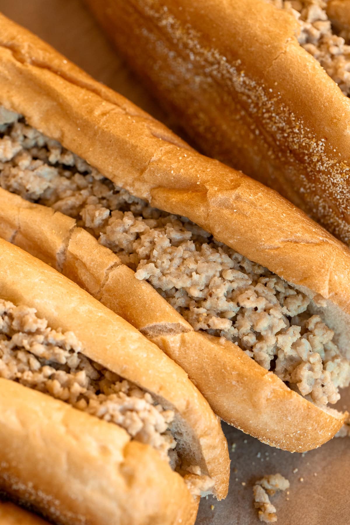 Close up detail of ground chicken with melted Cooper Sharp cheese inside Amoroso rolls for chicken cheesesteaks.