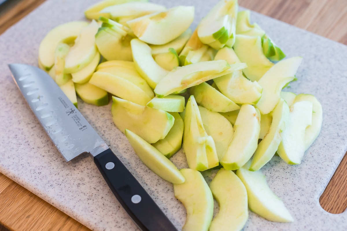 peeled, cored, and sliced apples on a cutting board.