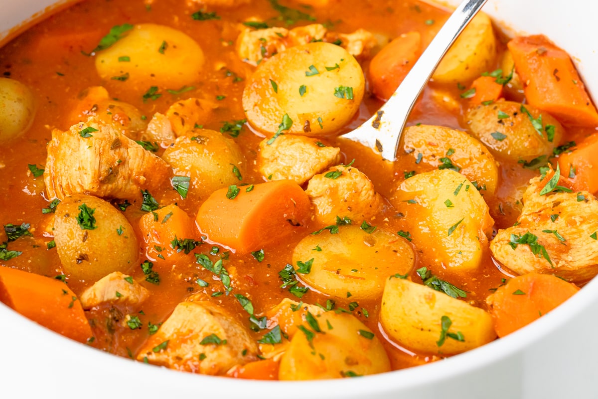 chicken stew with a tomato base and carrots and potatoes.