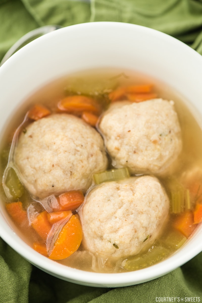 matzo ball soup in a bowl with veggies.