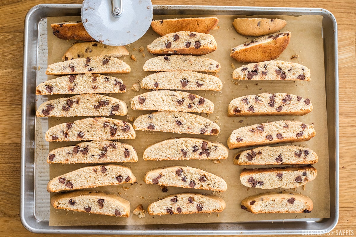 sliced mandel bread on a baking sheet with a pizza cutter on the top left