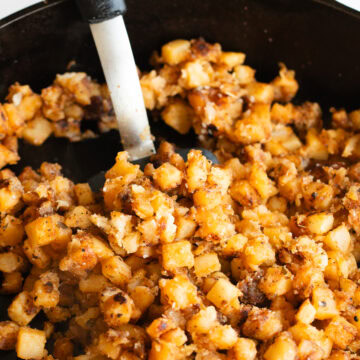 home fries in a cast iron skillet with a spatula.