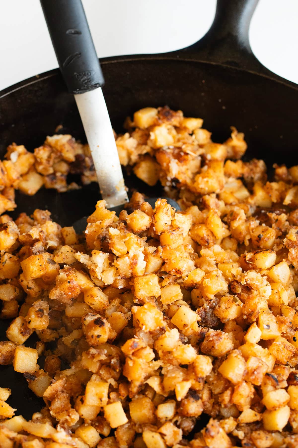 home fries in a cast iron skillet with a spatula.