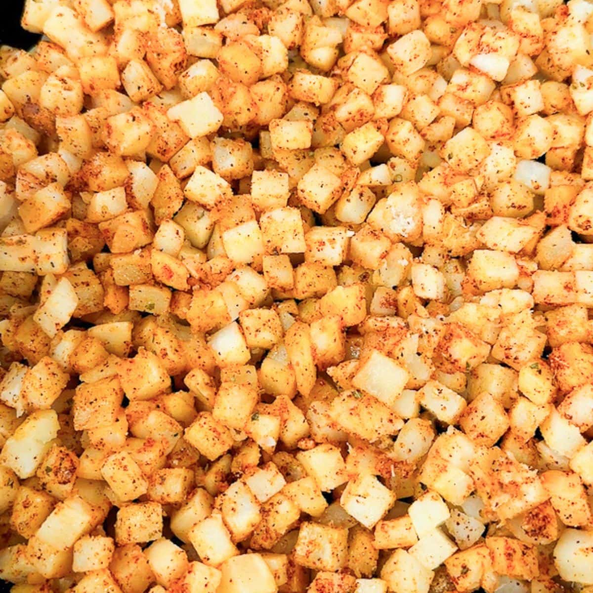 uncooked seasoned home fries in a skillet.