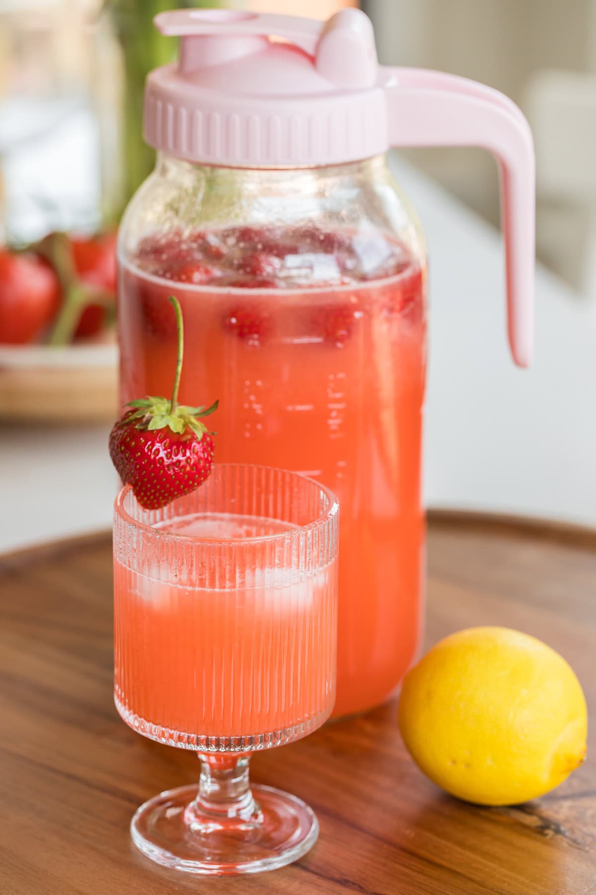 fresh strawberry lemonade recipe in a glass and a pitcher.