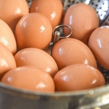 Steamed Hard Boiled Eggs results in an easy to peel hard boiled egg every time! Steaming hard boiled eggs allows you to skip waiting to use older eggs for hard boiling and you can use fresh eggs without any issues. Perfect for deviled eggs and of course Easter recipes ! eggs in steamer basket