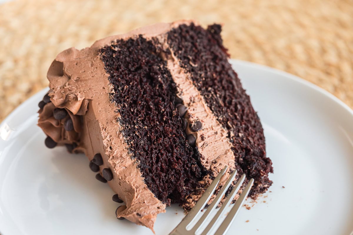 chocolate cake with chocolate buttercream on a white plate with a fork.