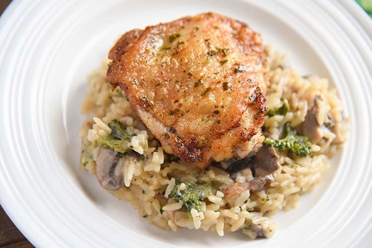 crispy chicken thighs over mushroom broccoli rice on a plate