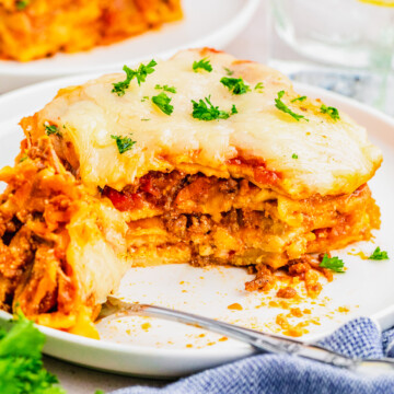 lasagna bolognese on a plate with a fork and bite full taken out.