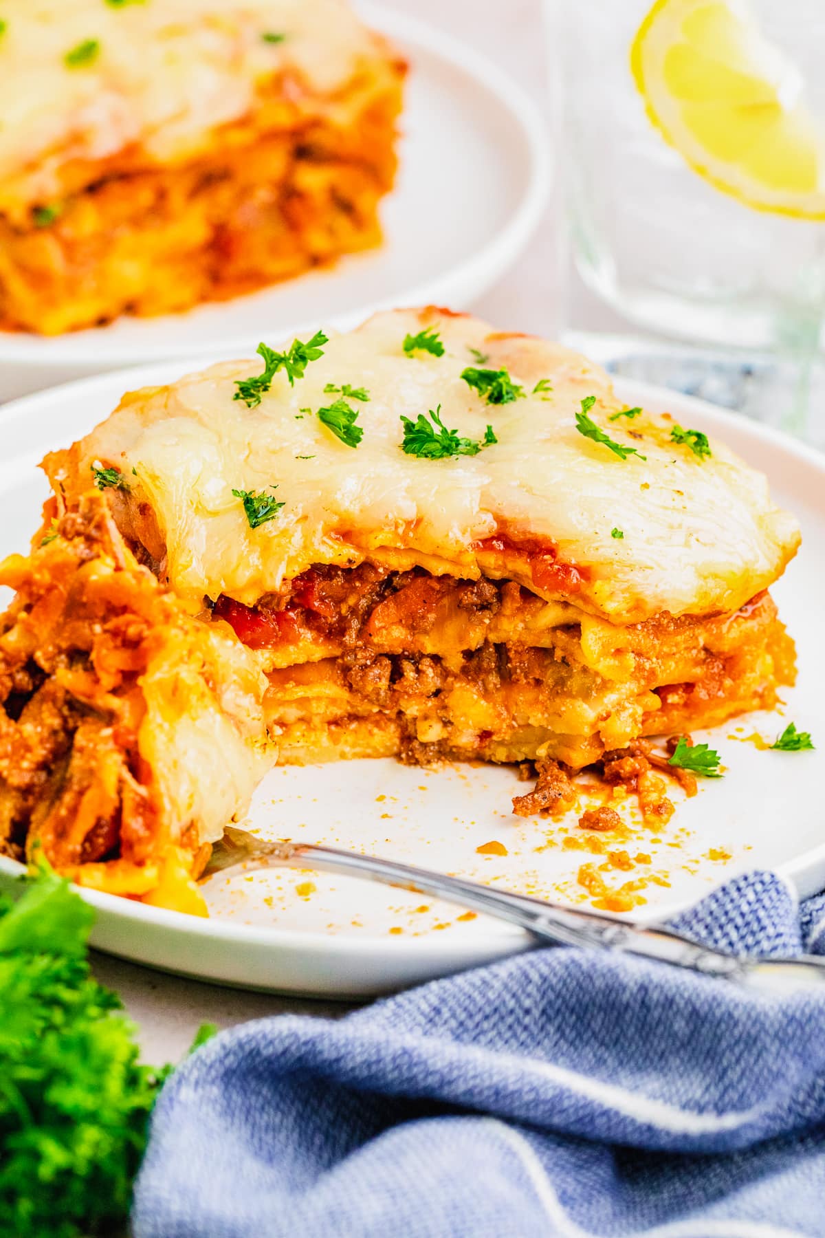lasagna bolognese on a plate with a fork and bite full taken out.