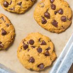 pumpkin chocolate chip cookies on parchment paper on a sheet pan