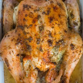 whole roasted chicken with herbs in a casserole dish