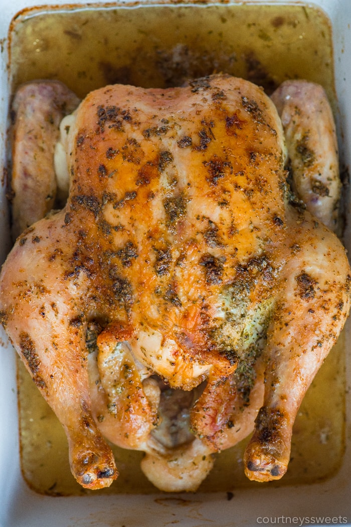 whole roasted chicken with herbs in a casserole dish