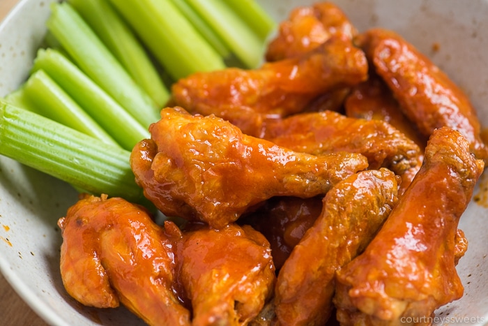 air fried crispy chicken wings with hot sauce in a bowl with celery