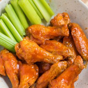 Air Fryer Chicken wings with hot sauce and celery in a bowl