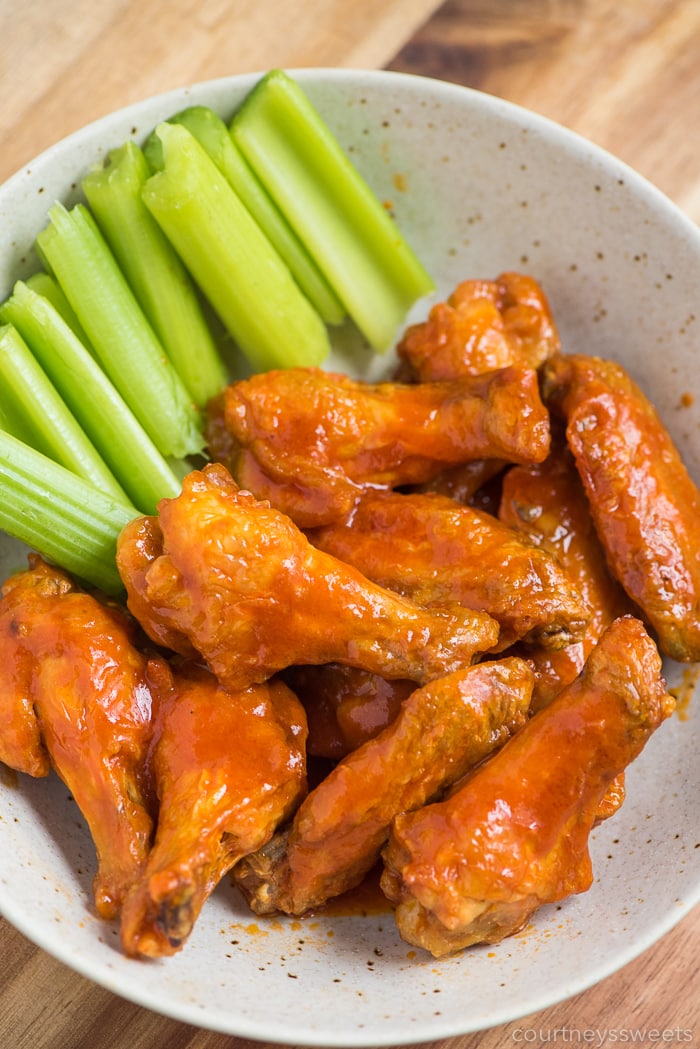 Air Fryer Chicken wings with hot sauce and celery in a bowl 