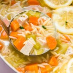lemon chicken orzo soup in a pot with a ladle taking a serving.