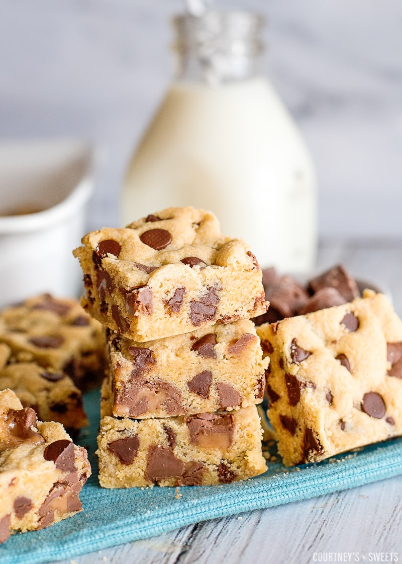 chocolate chip cookie bars on a teal napkin with milk cup in background