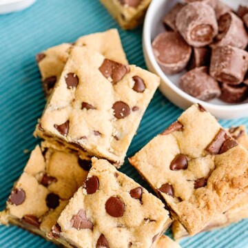 overhead photo of chocolate chip cookie bars with rolo candies in a bowl on a teal napkin