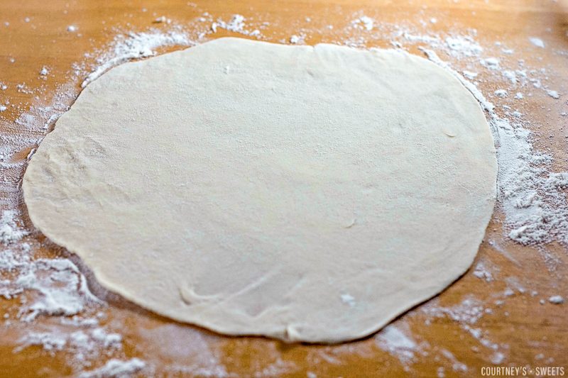 flattened raw tortilla dough on a floured surface