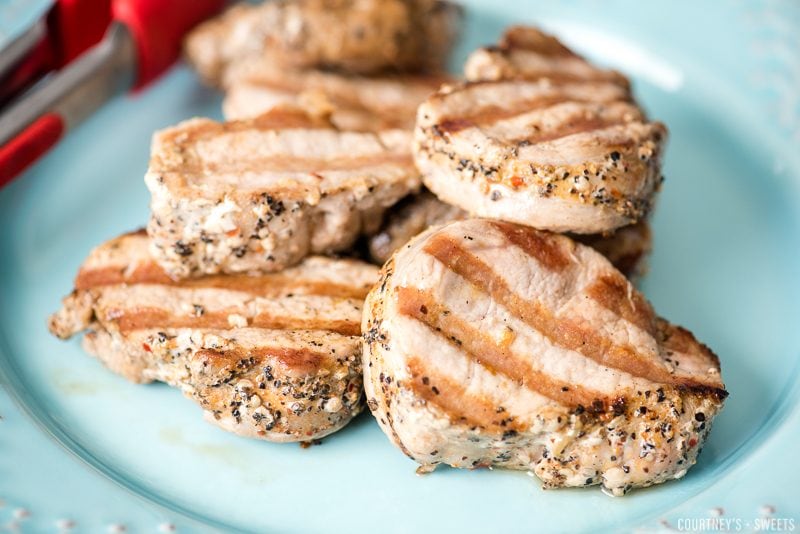resting pork loin on a blue plate with red tongs