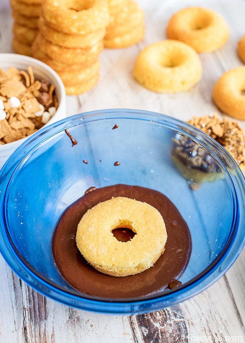 dipping cake mix donut into chocolate donut frosting