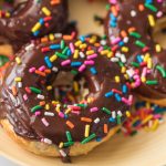 air fryer donuts with chocolate glaze and sprinkles on a yellow plate