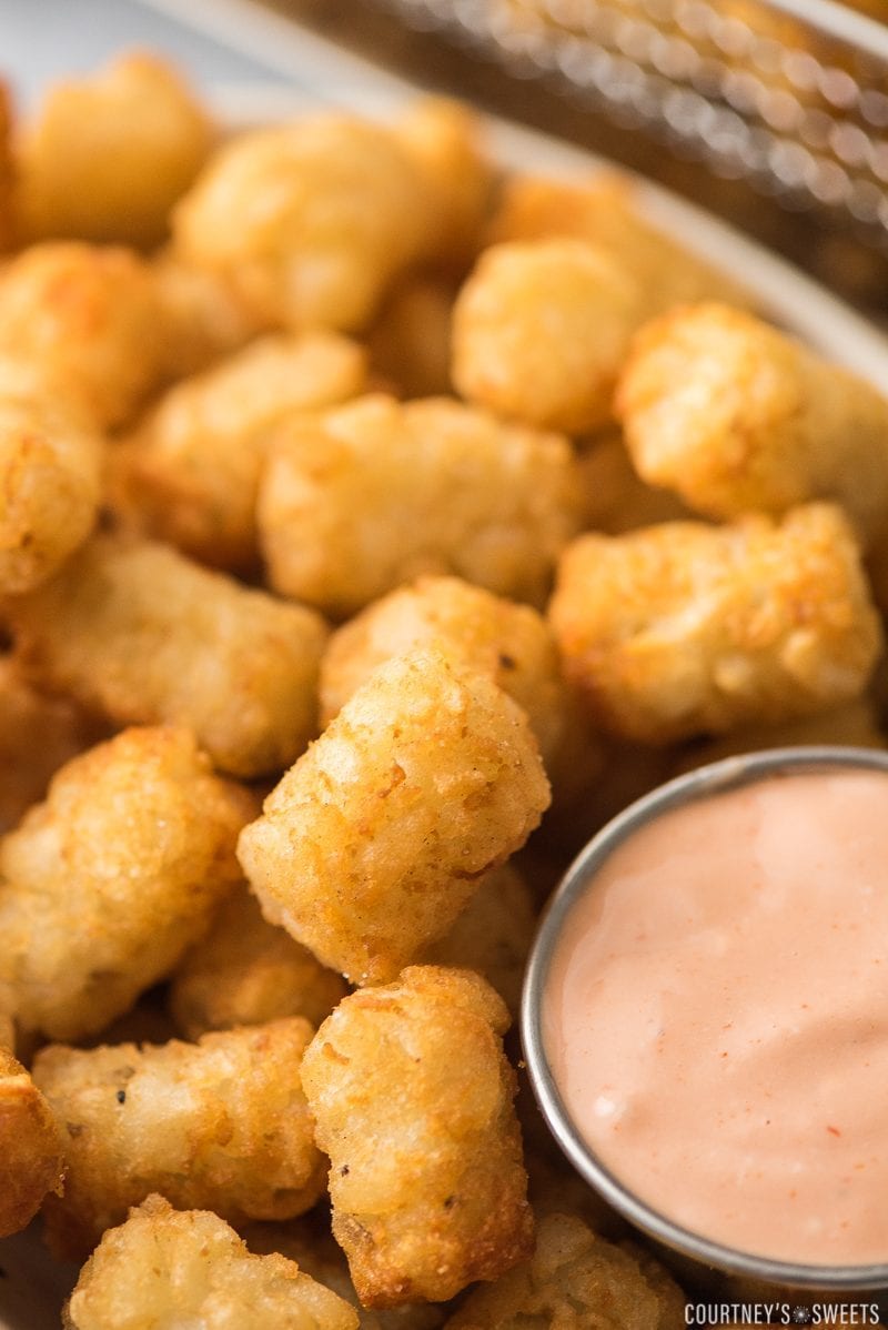 close up of tater tots with fry sauce in a dipping cup