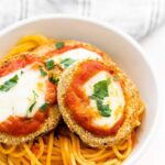 air fryer eggplant parmesan in a white bowl over spaghetti with sauce