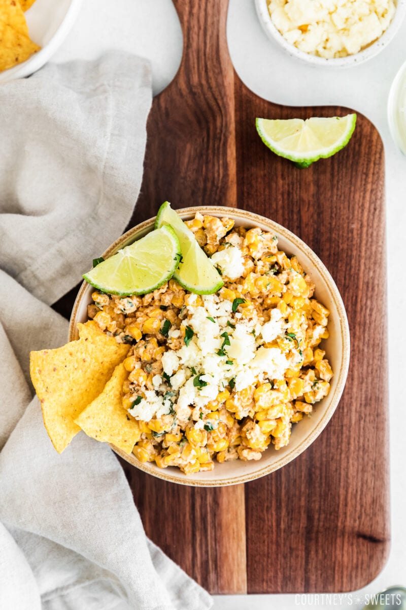 elote corn dip in low bowl on wooden cutting board with chips 