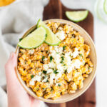 hand holding elote corn dip in low bowl