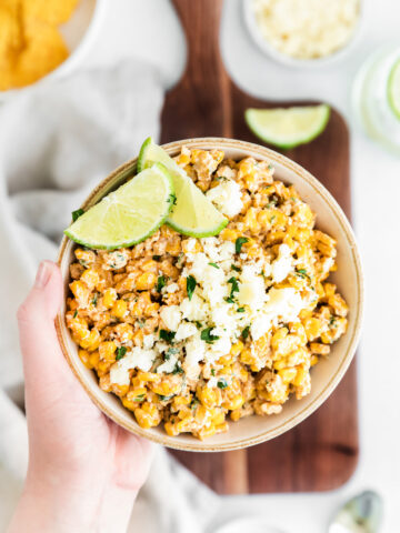 hand holding elote corn dip in low bowl