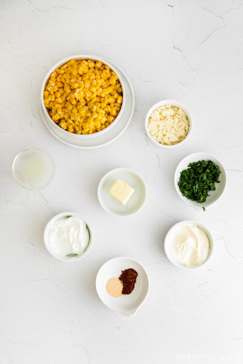 elote dip ingredients in small bowls on gray slab