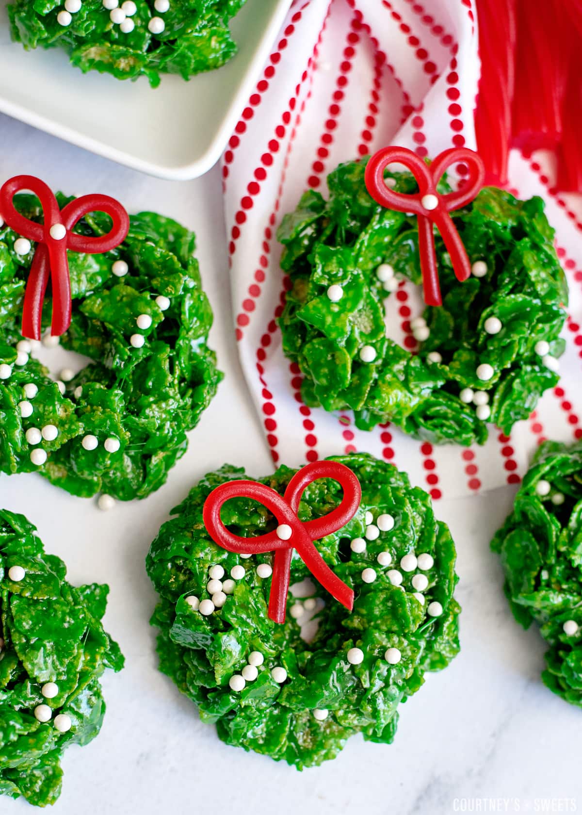 cornflake wreath cookies with twizzler bows on a marble slab with striped red napkin on the top right