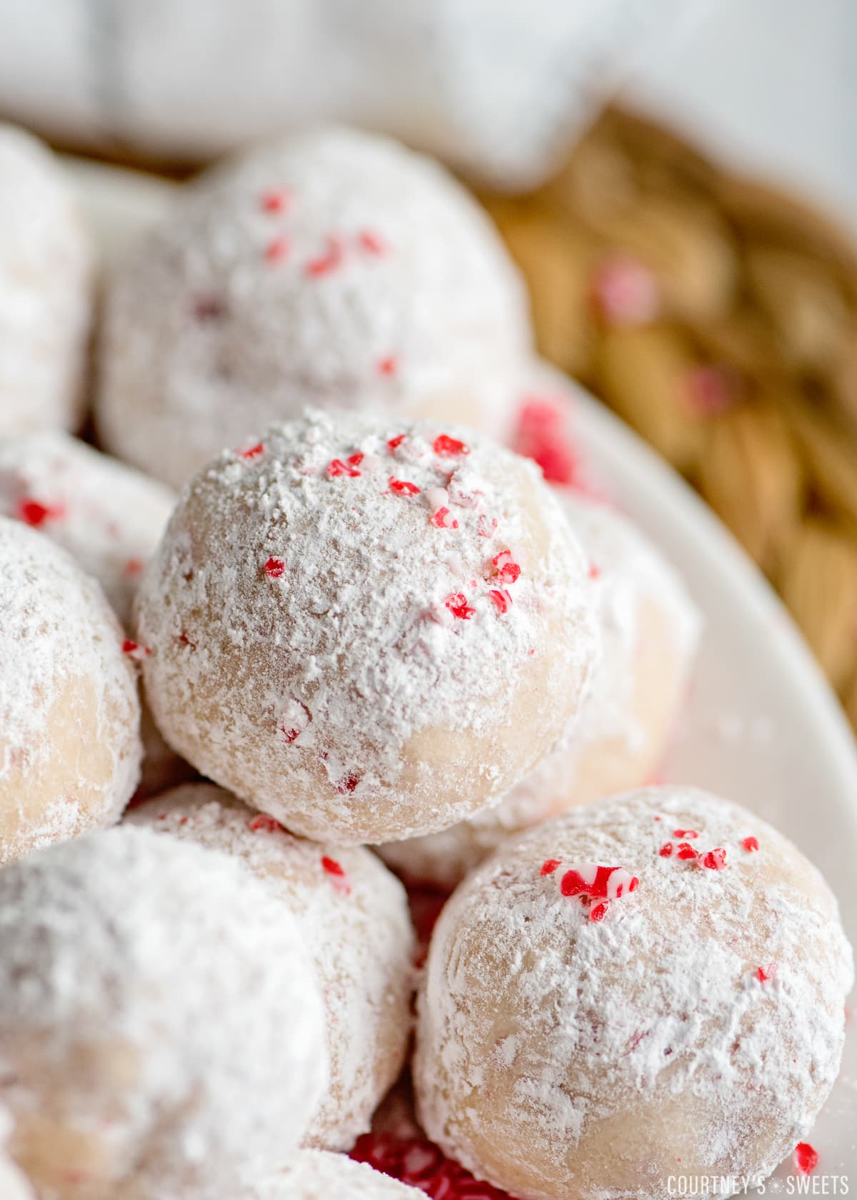 peppermint snow ball cookies on a tray with sprinkled peppermint candy on top