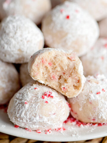 peppermint snow ball cookies on a tray with one cut in half