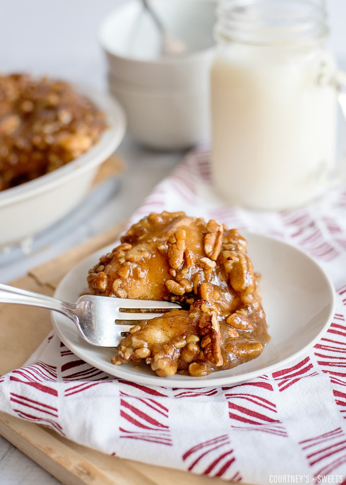 stick bun with pecans and a fork cutting a bite on a plate on a red and white napkin