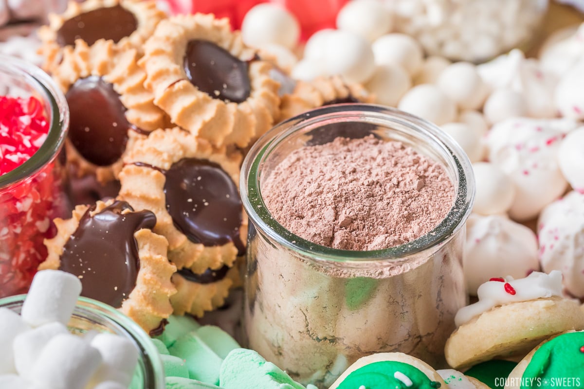 hot chocolate mix in a glass jar surrounded by sweets