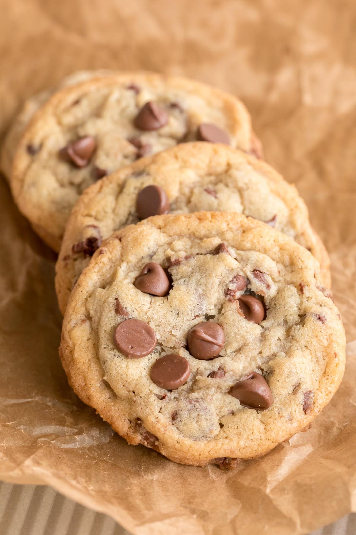 fresh made chocolate chip cookie recipe showing four cookies on a piece of parchment.