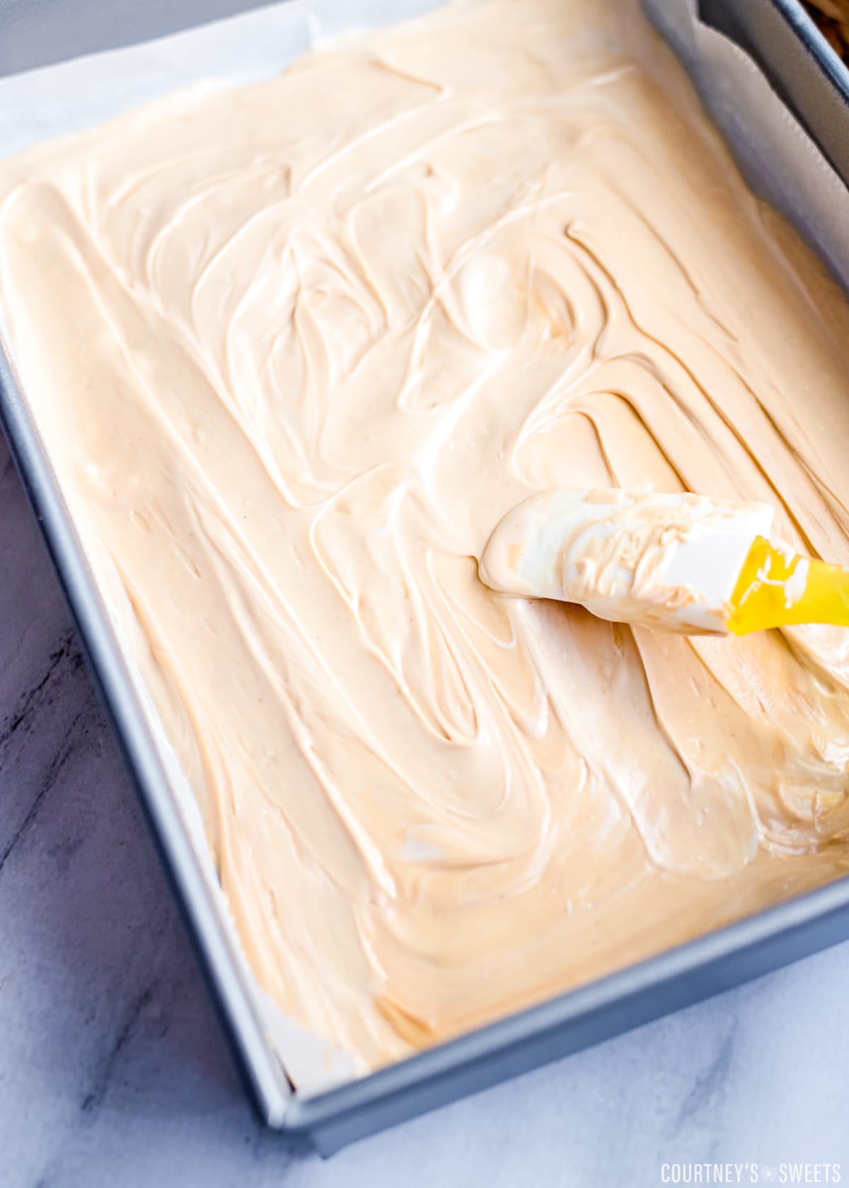 spatula spreading out melted white chocolate and peanut butter