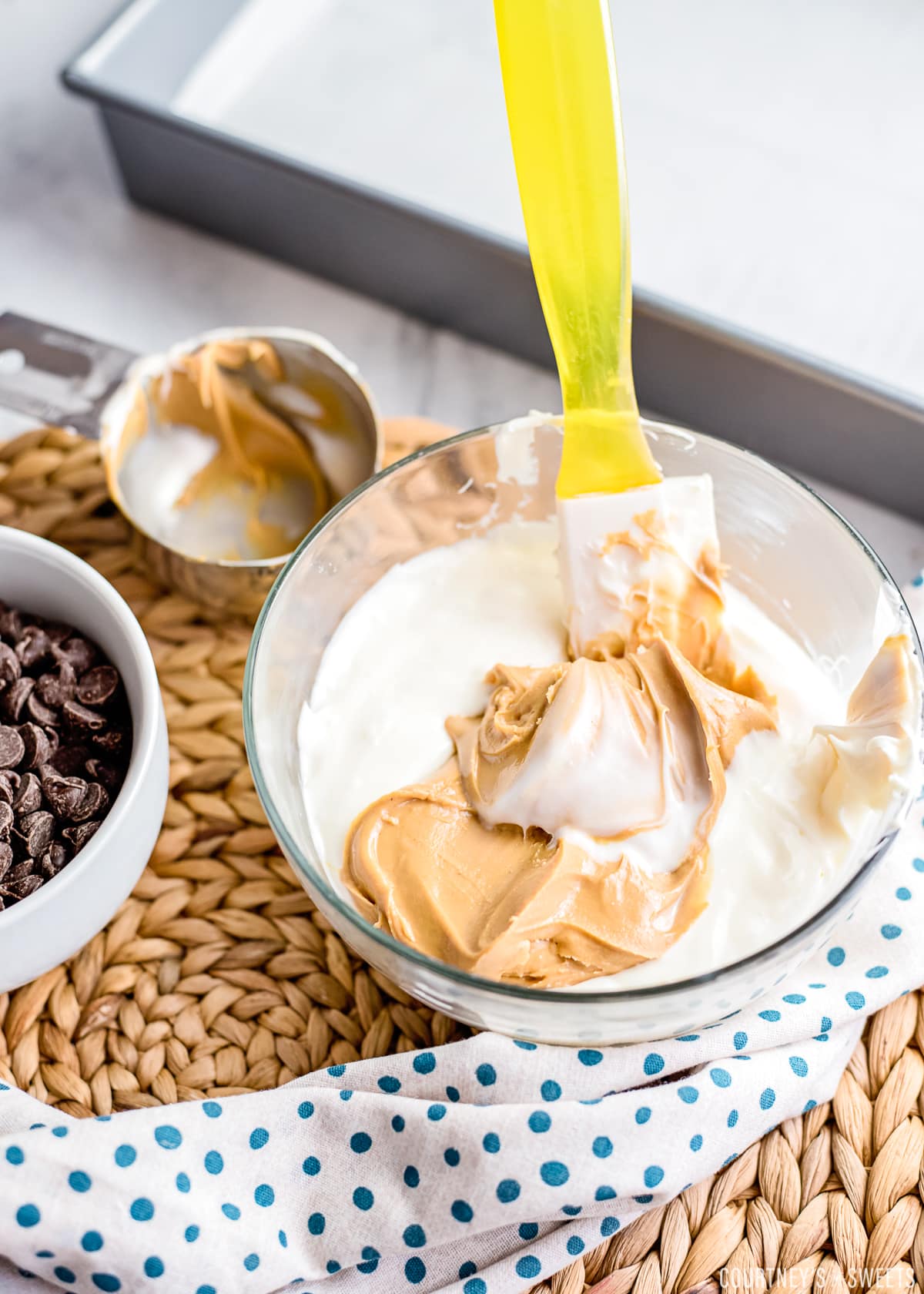 yellow spatula in bowl mixing white chocolate and peanut butter