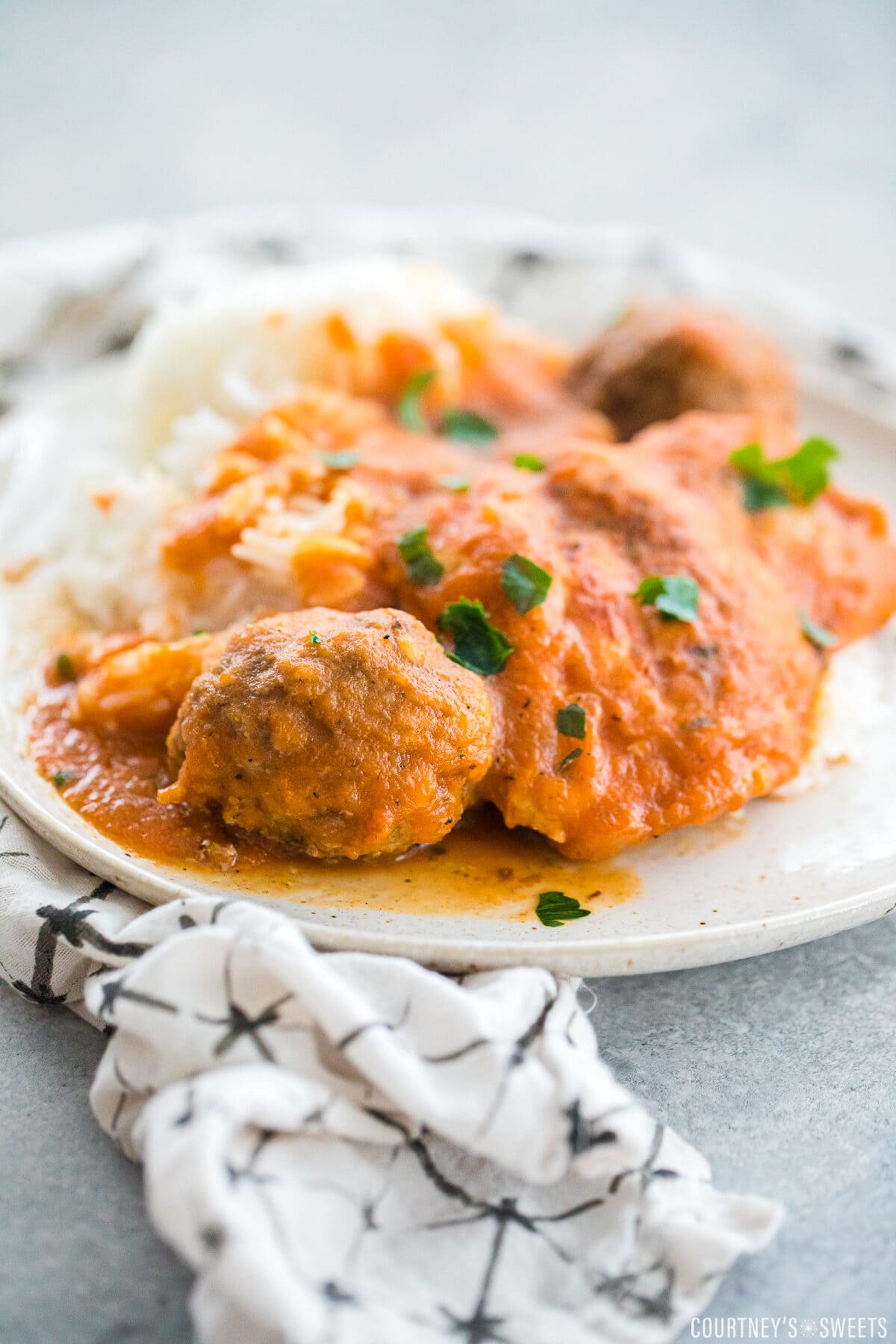 grandma's chicken friccassee with meatballs on a plate resting on a white napkin with with black details.