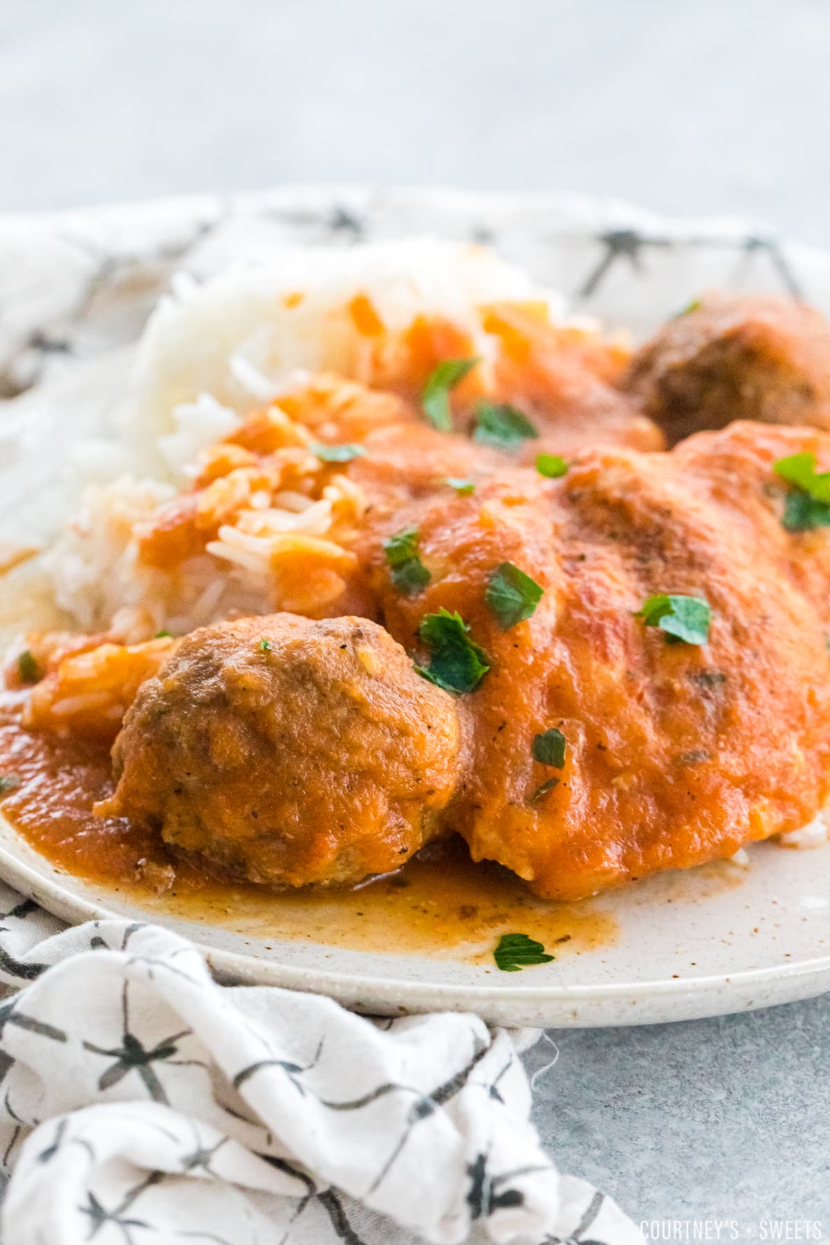 grandma's chicken friccassee with meatballs on a plate resting on a white napkin with black lines.