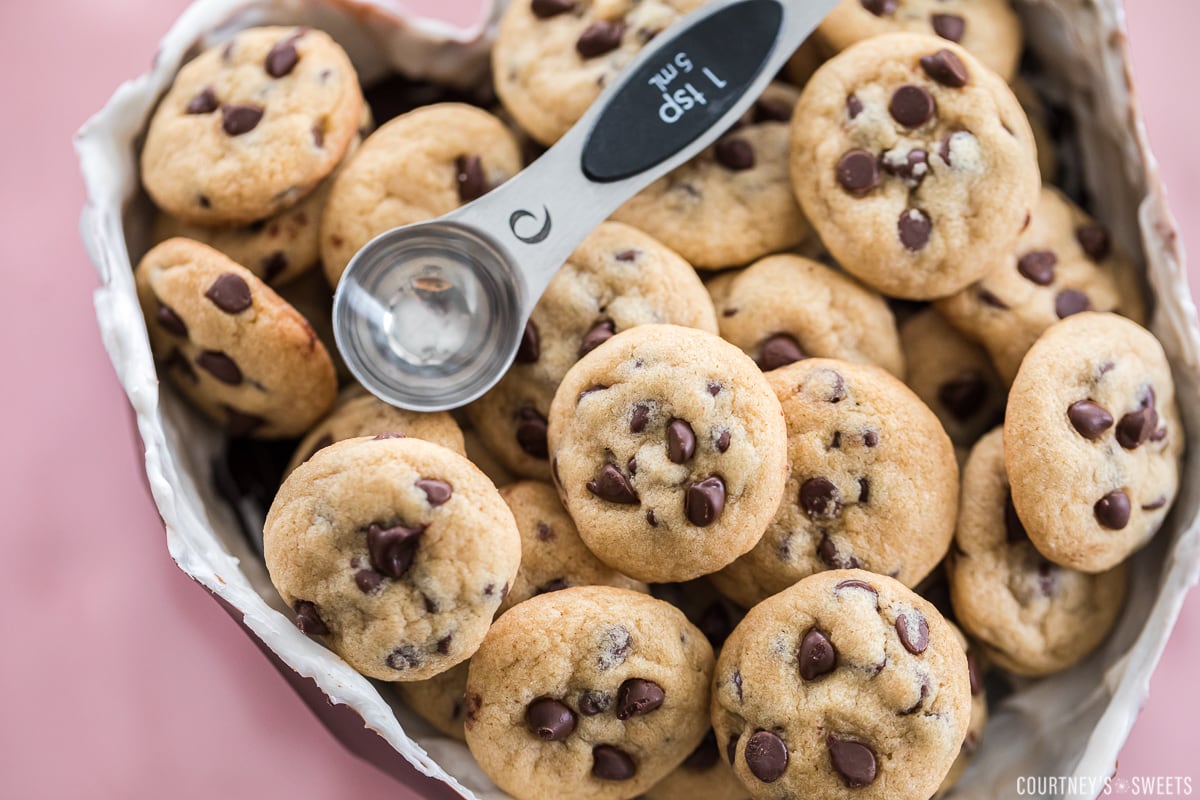 mini chocolate chip cookies in a chocolate molded heart with a teaspoon measuring spoon to show size on top of the cookies. 