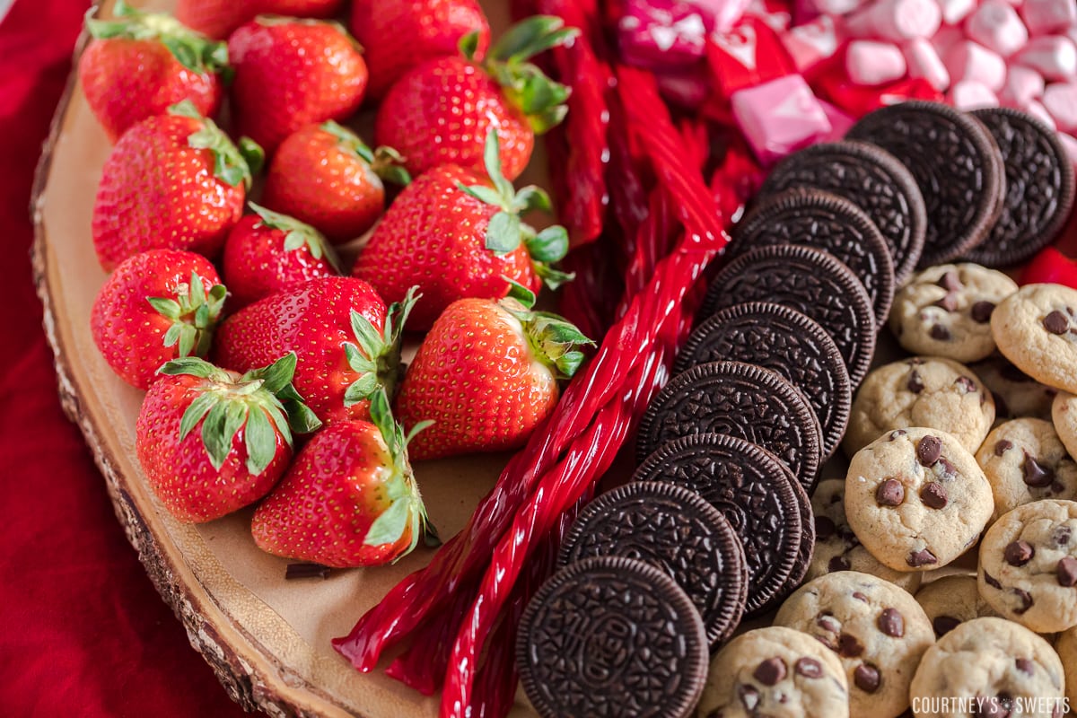strawberries twizzlers and oreos on a charcuterie board close up photo.